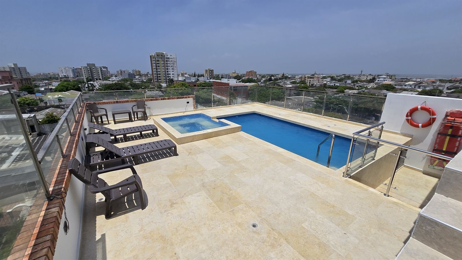 Zona social de la azotea con asoleadoras junto a la piscina